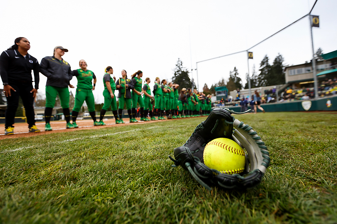 A softball and mitt lay on the ground as the Oregon softball team lines up for the national anthem before the start of the game. The Oregon Ducks play the Oregon State Beavers at Howe Field in Eugene, Oregon on March 15, 2015. (Ryan Kang/Emerald)